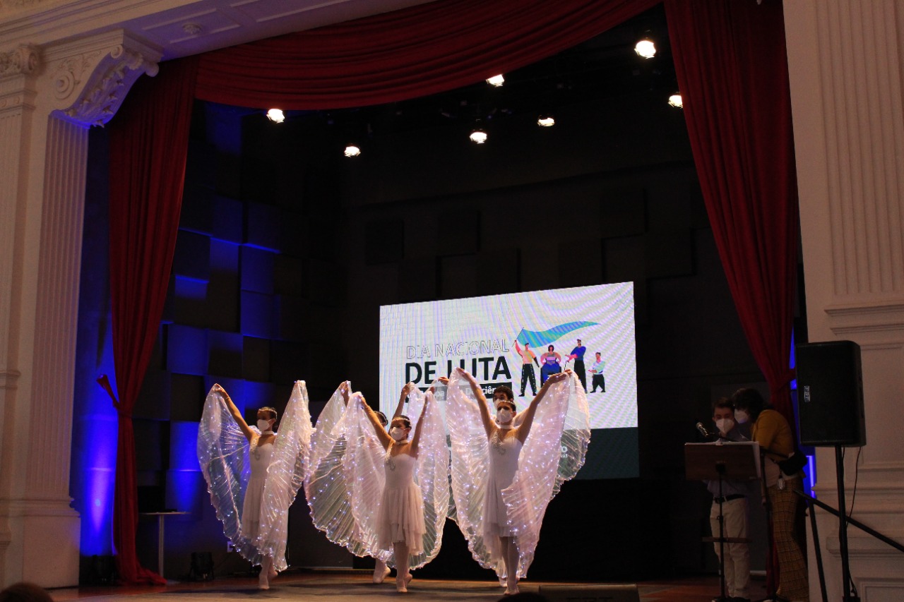 cinco bailarinas no palco do evento, Elas usam vestidos brancos com luzes de led azul no vestido.
